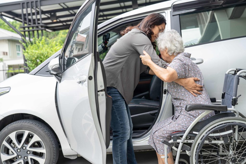 Older woman being assisted into car